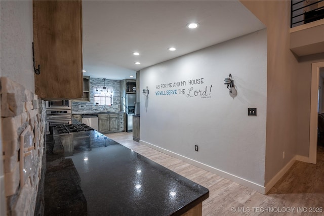 kitchen featuring stainless steel appliances, dark stone countertops, light hardwood / wood-style floors, and tasteful backsplash