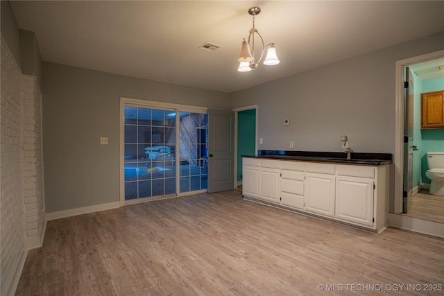 kitchen featuring decorative light fixtures, a notable chandelier, sink, light hardwood / wood-style flooring, and white cabinets