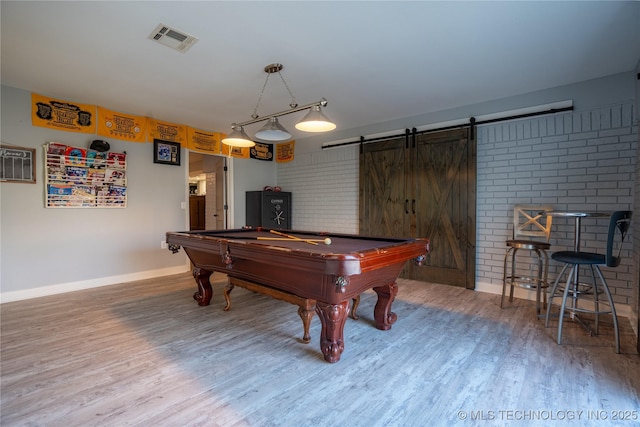 recreation room with pool table, a barn door, and hardwood / wood-style floors