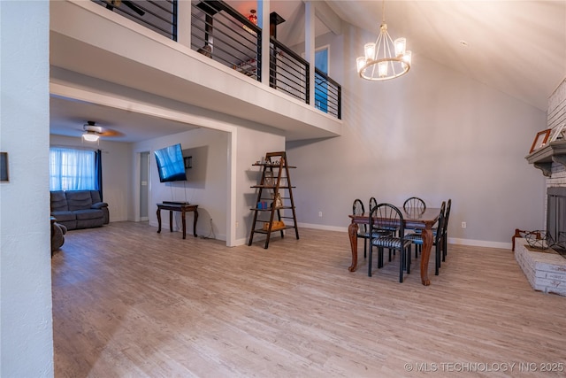 dining space with high vaulted ceiling, ceiling fan with notable chandelier, and hardwood / wood-style floors