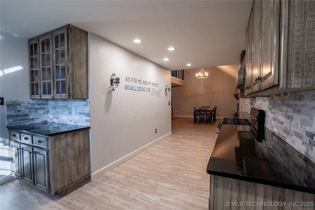 kitchen featuring light wood-type flooring, a chandelier, and backsplash