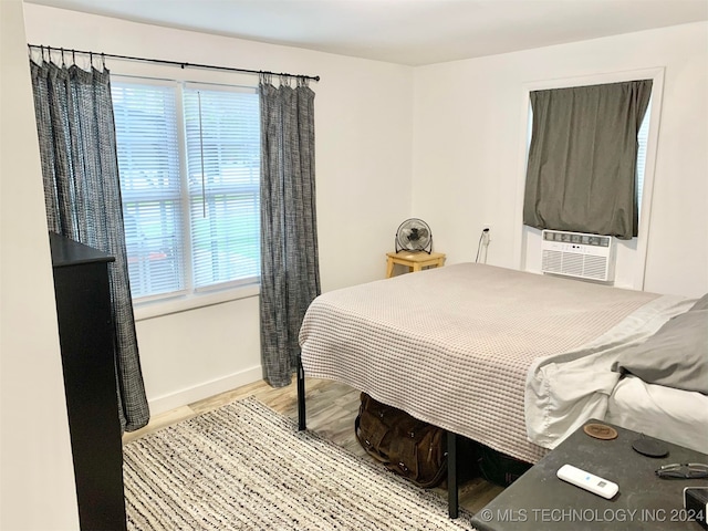 bedroom with cooling unit and light hardwood / wood-style floors