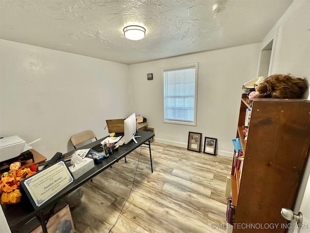 office area with light wood-type flooring and a textured ceiling