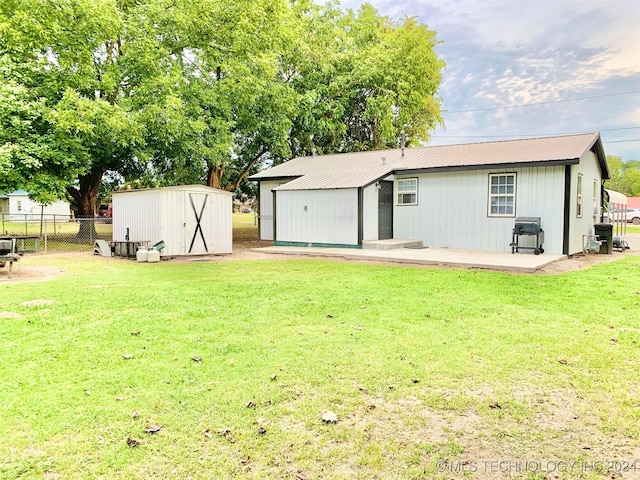 rear view of property with a yard, a patio area, and a storage shed