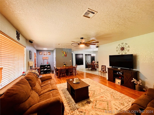 living room with ceiling fan, wood-type flooring, and a textured ceiling