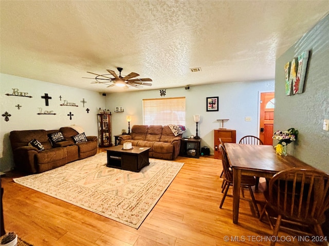 living room with hardwood / wood-style flooring, ceiling fan, and a textured ceiling