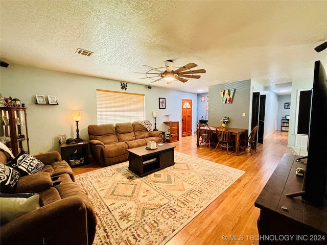 living room with hardwood / wood-style flooring, ceiling fan, and a textured ceiling