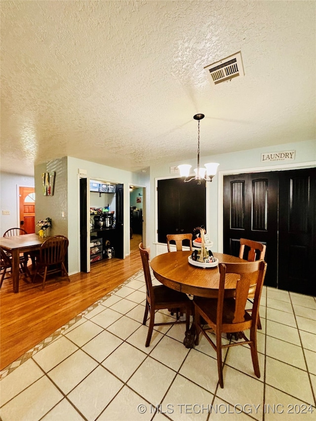 dining room featuring an inviting chandelier, a textured ceiling, and light wood-type flooring