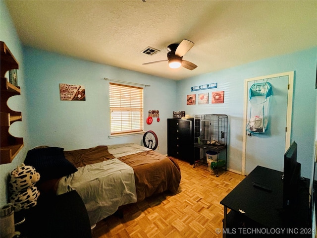 bedroom with a textured ceiling, ceiling fan, and light parquet flooring