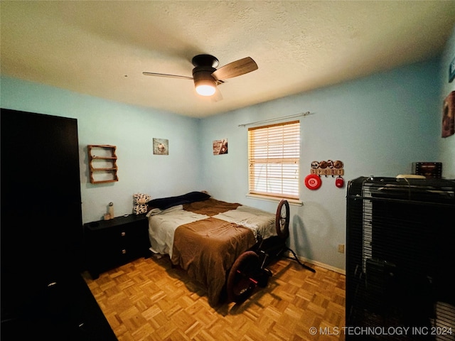 bedroom with a textured ceiling, light parquet floors, and ceiling fan