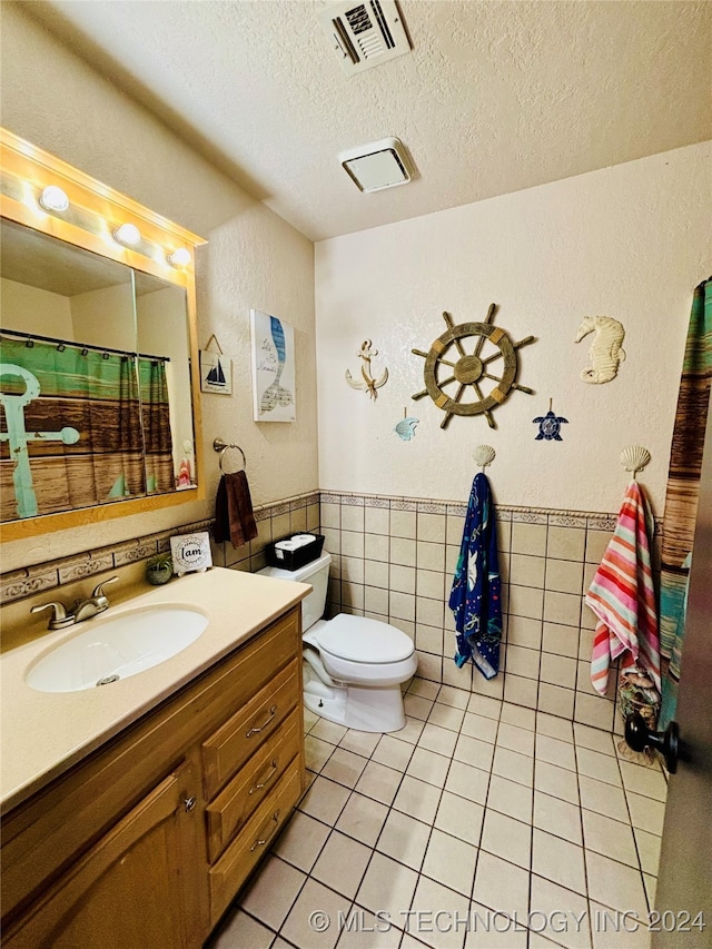 bathroom featuring tile patterned flooring, a textured ceiling, toilet, and tile walls