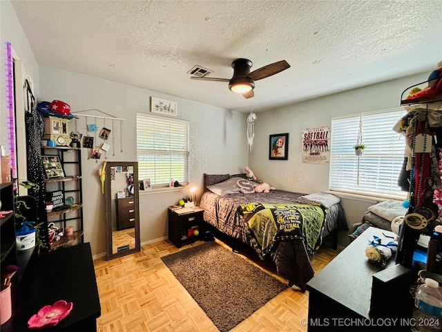 bedroom featuring ceiling fan, a textured ceiling, and light parquet floors