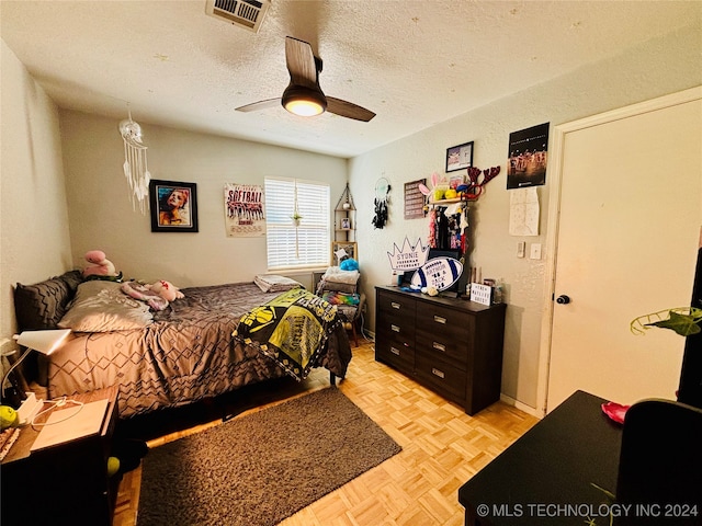 bedroom featuring ceiling fan, light parquet floors, and a textured ceiling