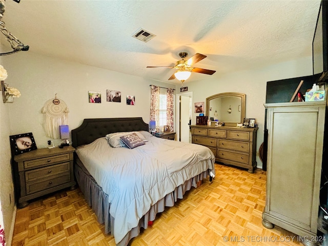 bedroom featuring ceiling fan, a textured ceiling, and light parquet floors