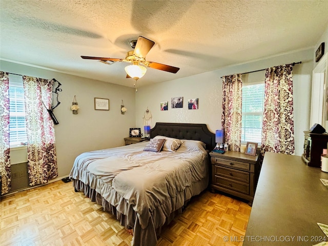 bedroom with ceiling fan, light parquet floors, and a textured ceiling