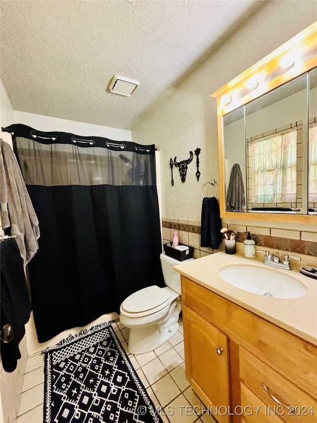 bathroom featuring tile patterned flooring, vanity, toilet, and a textured ceiling