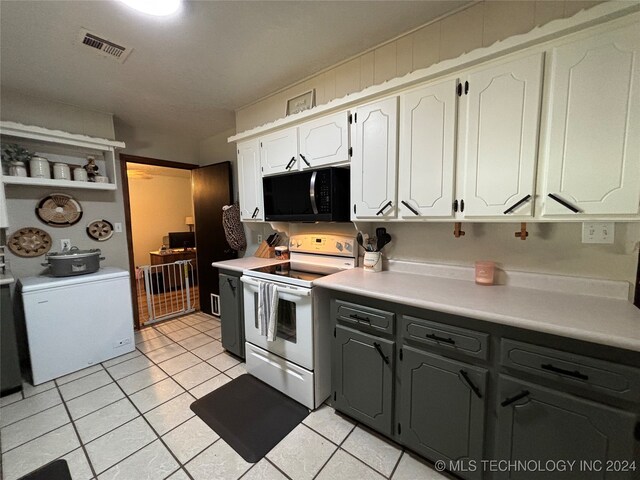 kitchen featuring refrigerator, white cabinetry, stainless steel range with electric stovetop, and light tile patterned flooring