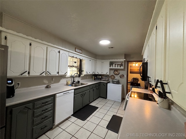 kitchen with range, white dishwasher, sink, white cabinetry, and washer / clothes dryer