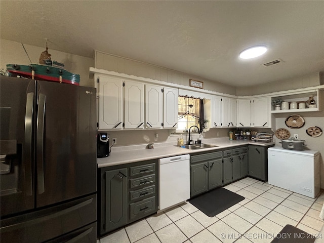 kitchen with stainless steel fridge, sink, light tile patterned floors, dishwasher, and white cabinetry