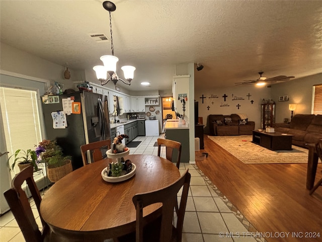 dining room featuring ceiling fan with notable chandelier, sink, light wood-type flooring, and a textured ceiling