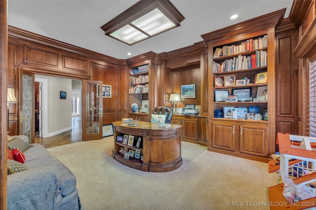 office space featuring ornamental molding, built in shelves, wooden walls, and light carpet