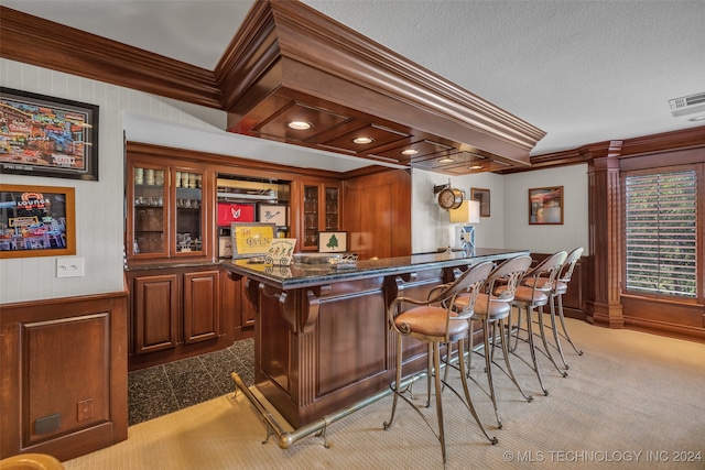 bar featuring a textured ceiling, ornamental molding, and light colored carpet