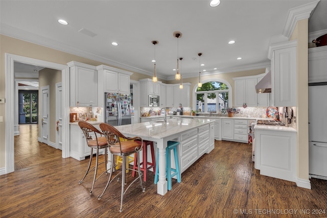 kitchen with hanging light fixtures, an island with sink, light stone counters, white cabinets, and stainless steel appliances