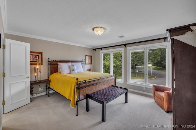 bedroom with ornamental molding and light colored carpet