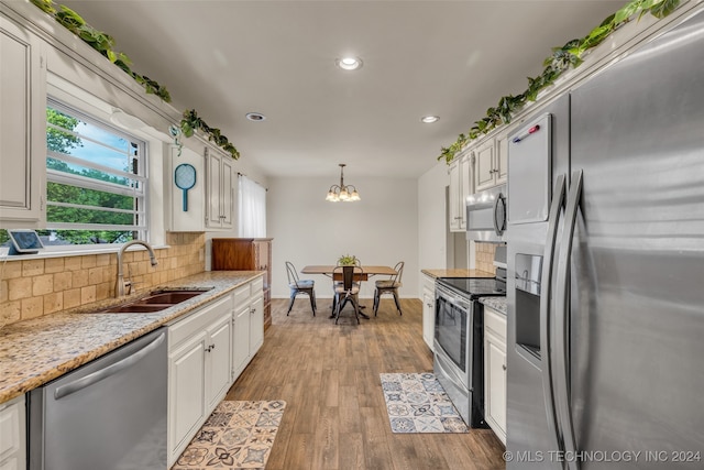 kitchen featuring hanging light fixtures, sink, white cabinetry, appliances with stainless steel finishes, and light hardwood / wood-style floors