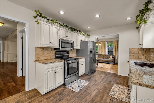 kitchen featuring decorative backsplash, white cabinets, dark hardwood / wood-style flooring, appliances with stainless steel finishes, and light stone countertops