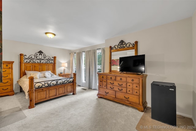 bedroom with light carpet and fridge