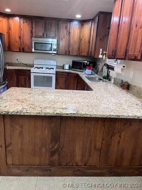 kitchen featuring light tile patterned flooring, sink, light stone counters, and gas range gas stove