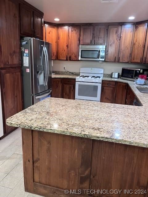 kitchen featuring light stone counters, light tile patterned flooring, and appliances with stainless steel finishes