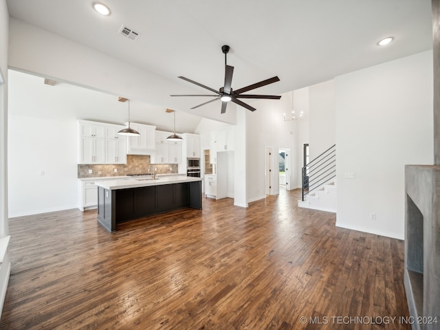 unfurnished living room with ceiling fan with notable chandelier, dark hardwood / wood-style flooring, high vaulted ceiling, and sink