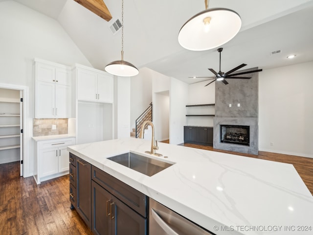 kitchen with pendant lighting, dark wood-type flooring, sink, light stone countertops, and white cabinetry