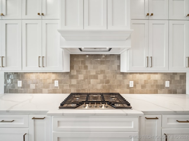 kitchen featuring tasteful backsplash, light stone counters, white cabinets, and stainless steel gas cooktop