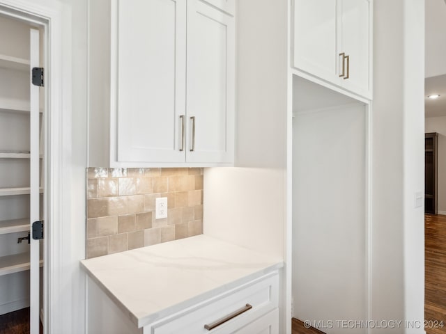 kitchen with light stone countertops, backsplash, dark hardwood / wood-style floors, and white cabinetry