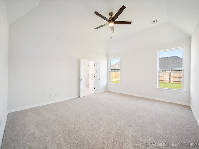 spare room featuring light colored carpet, vaulted ceiling, a wealth of natural light, and ceiling fan