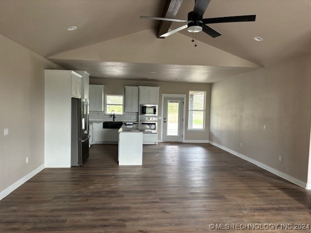 unfurnished living room with dark wood-type flooring, ceiling fan, sink, and lofted ceiling with beams