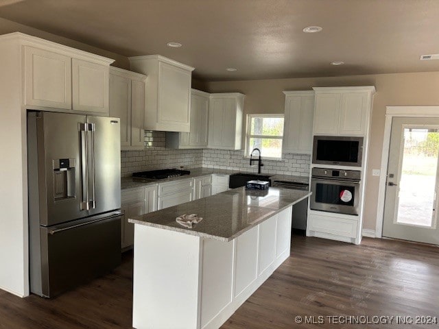 kitchen featuring a wealth of natural light, dark hardwood / wood-style flooring, appliances with stainless steel finishes, and a center island