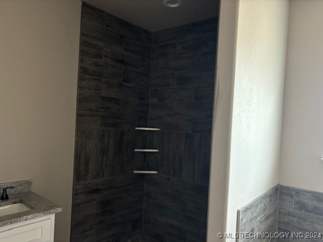 bathroom with a tile shower and vanity