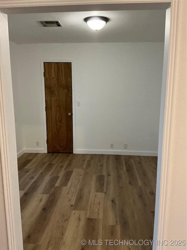 spare room with visible vents, baseboards, and wood finished floors