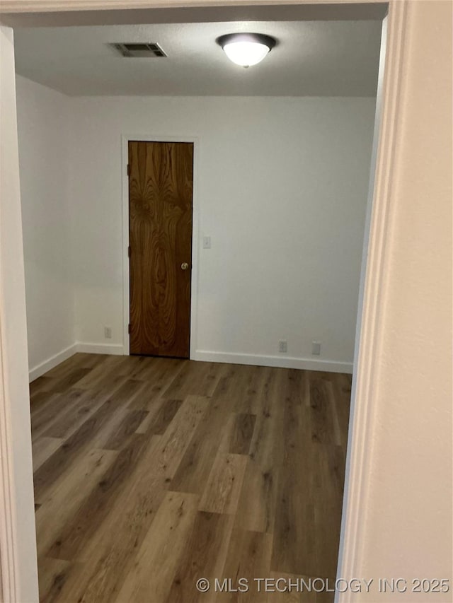 unfurnished room with visible vents, baseboards, and wood finished floors