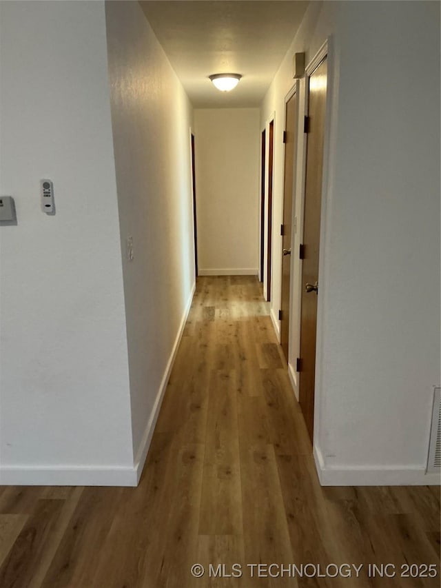 corridor featuring light wood-type flooring and baseboards