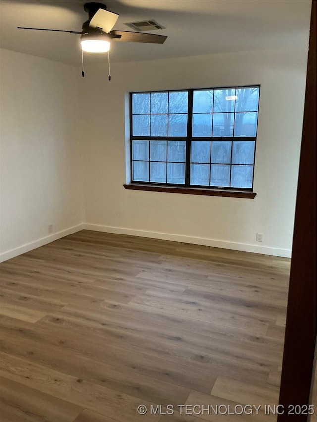 unfurnished room featuring a wealth of natural light, baseboards, visible vents, and wood finished floors