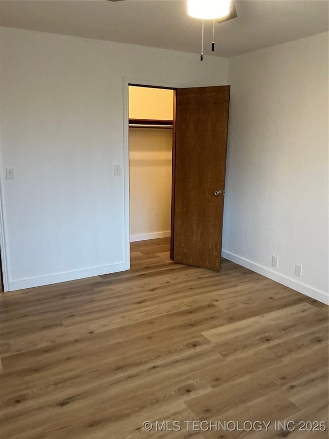 unfurnished bedroom featuring a closet, baseboards, and wood finished floors