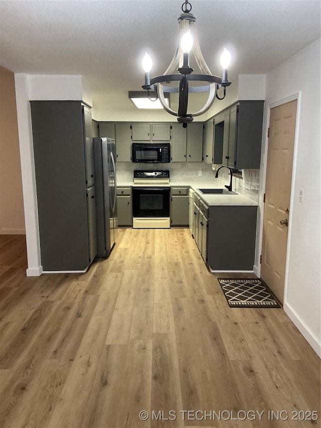 kitchen featuring a sink, light countertops, light wood-type flooring, backsplash, and black appliances