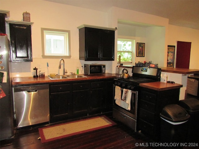 kitchen with dark hardwood / wood-style floors, tasteful backsplash, sink, kitchen peninsula, and stainless steel appliances