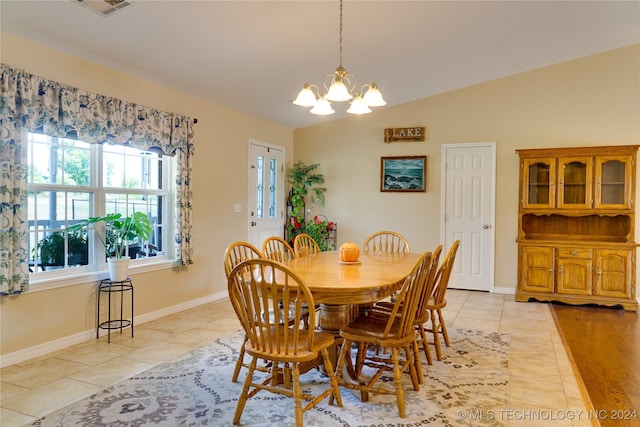 dining area with an inviting chandelier, lofted ceiling, and light tile patterned floors