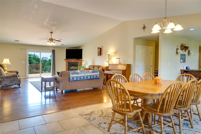 dining space featuring ceiling fan with notable chandelier, light hardwood / wood-style flooring, and vaulted ceiling